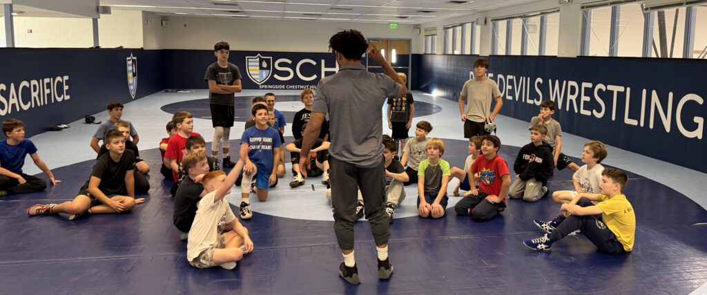 Chestnut Hill Wrestling Club Students Listening to a Coach discuss Wrestling moves in the S Chestnut Hill Wrestling Club in Philadelphia PA
